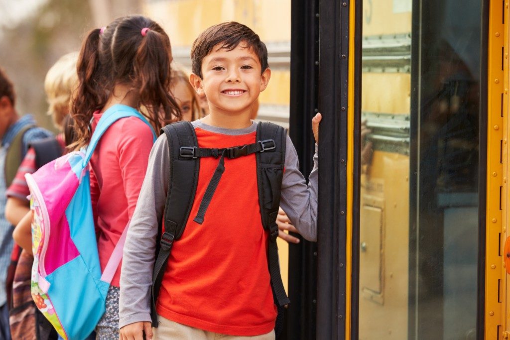 smiling kid beside the school bus