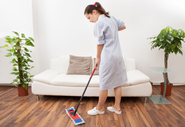 Portrait Of A Young Maid In Uniform Cleaning Floor With Mop