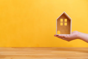 small home model in hand with yellow background