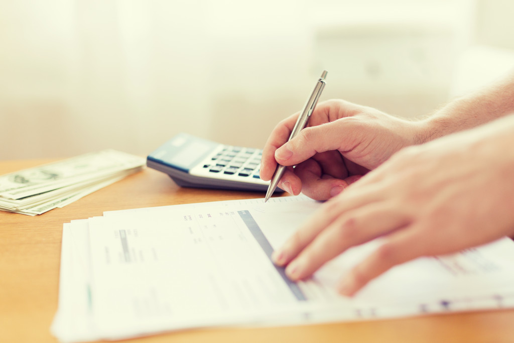 person signing utility bills with calculator on the side