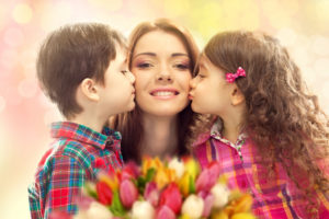 mother being kissed by her children on the cheeks