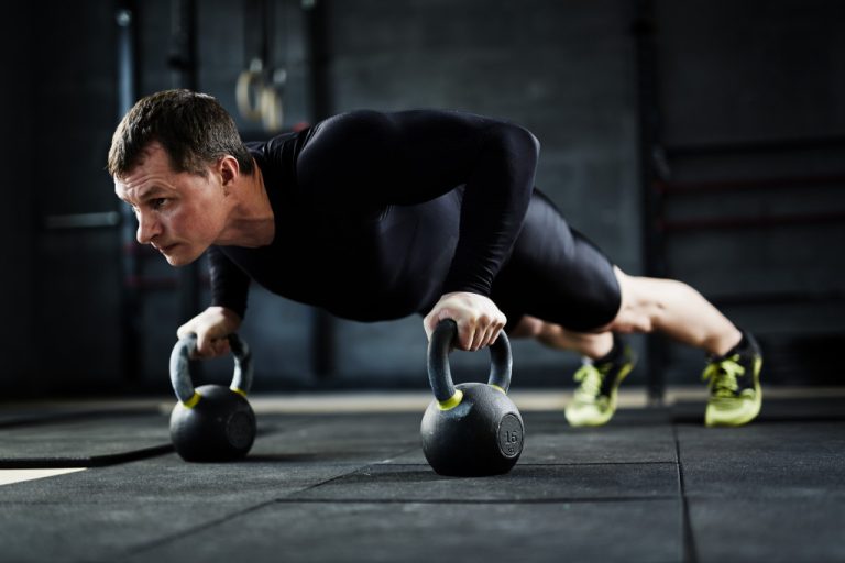 an active male adult planking with dumbbells