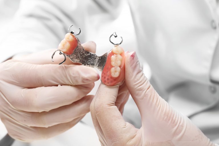 dentures being held by dentist and working on false teeth