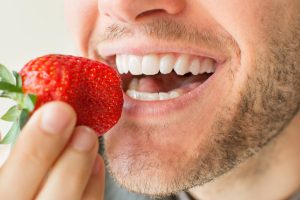 Shot of a man's mouth about to eat a strawberry