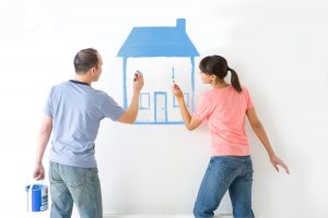 a couple painting an image of a house with blue paint on a white wall