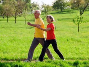 senior man and woman walking outdoors on a green field