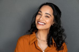 Close up face of young woman with beautiful smile isolated on grey wall with copy space