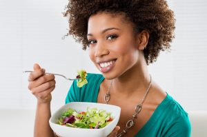 Young woman eating a salad at home.