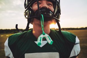 A football player after a game with his mouth guard hanging