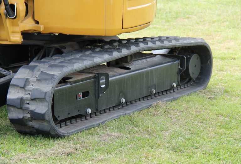 An excavator with rubber tracks on a grassy land