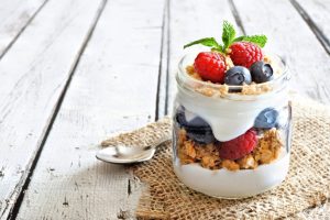 oats and yogurt in a mason jar with blueberries and mulberries as toppings