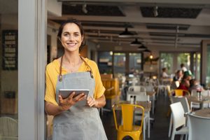 restaurant owner wearing apron and holding tablet in the entrance